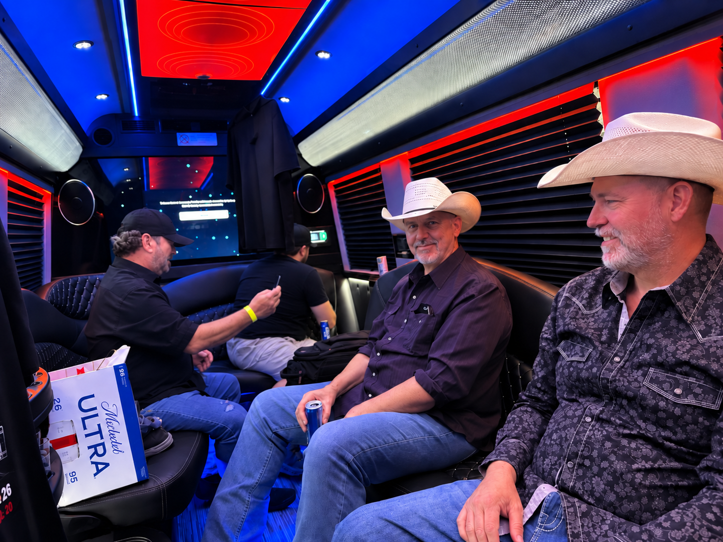 Passengers enjoying the luxury interior of an Elite Executive Travel van with comfortable seating and LED lighting.