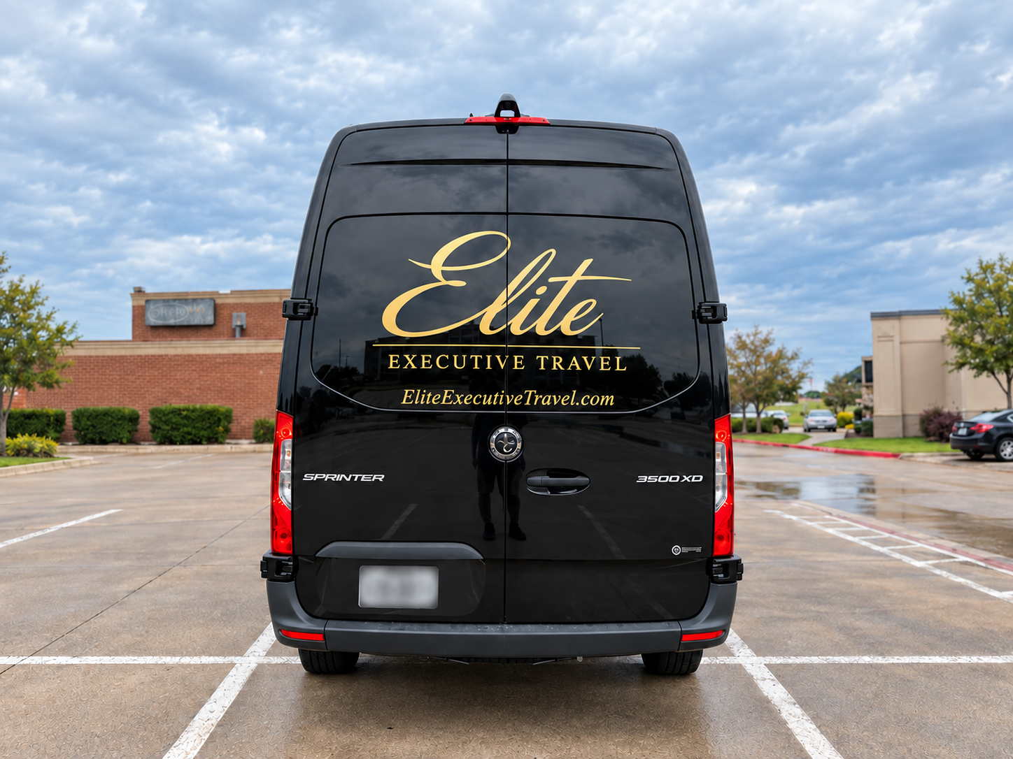 Rear view of an Elite Executive Travel van with gold company branding on the back.